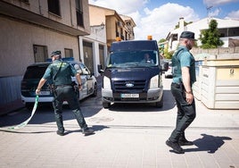 Agentes de la Guardia Civil abren el cordón policial para que salga el furgón de la funeraria tras el levantamiento de los cuerpos.