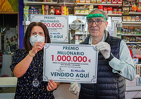 Dos loteros mostrando el premio millonario de Euromillones concedido en su establecimiento.