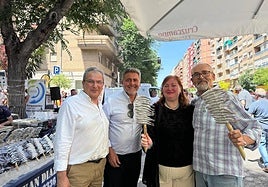 Representantes municipales y del comercio muestran espetos de sardinas.