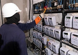 Dos técnicos de Endesa comprueban si hay fraude en un cuarto de contadores en un bloque de viviendas de Granada