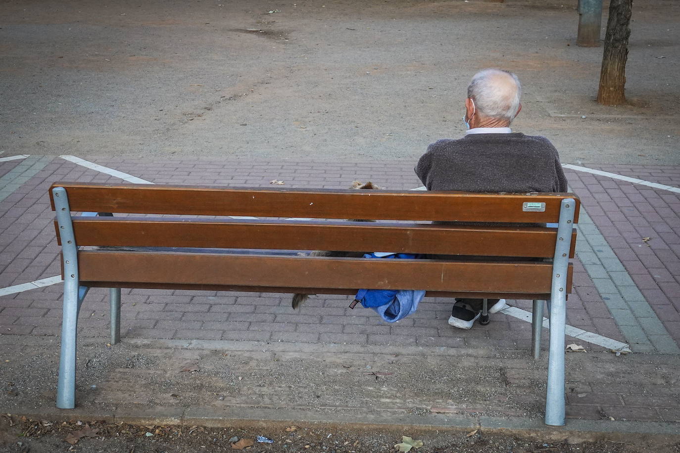 Un hombre mayor, sentado en un banco.