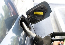 Una conductora extrae la manguera de repostaje de su vehículo en una gasolinera