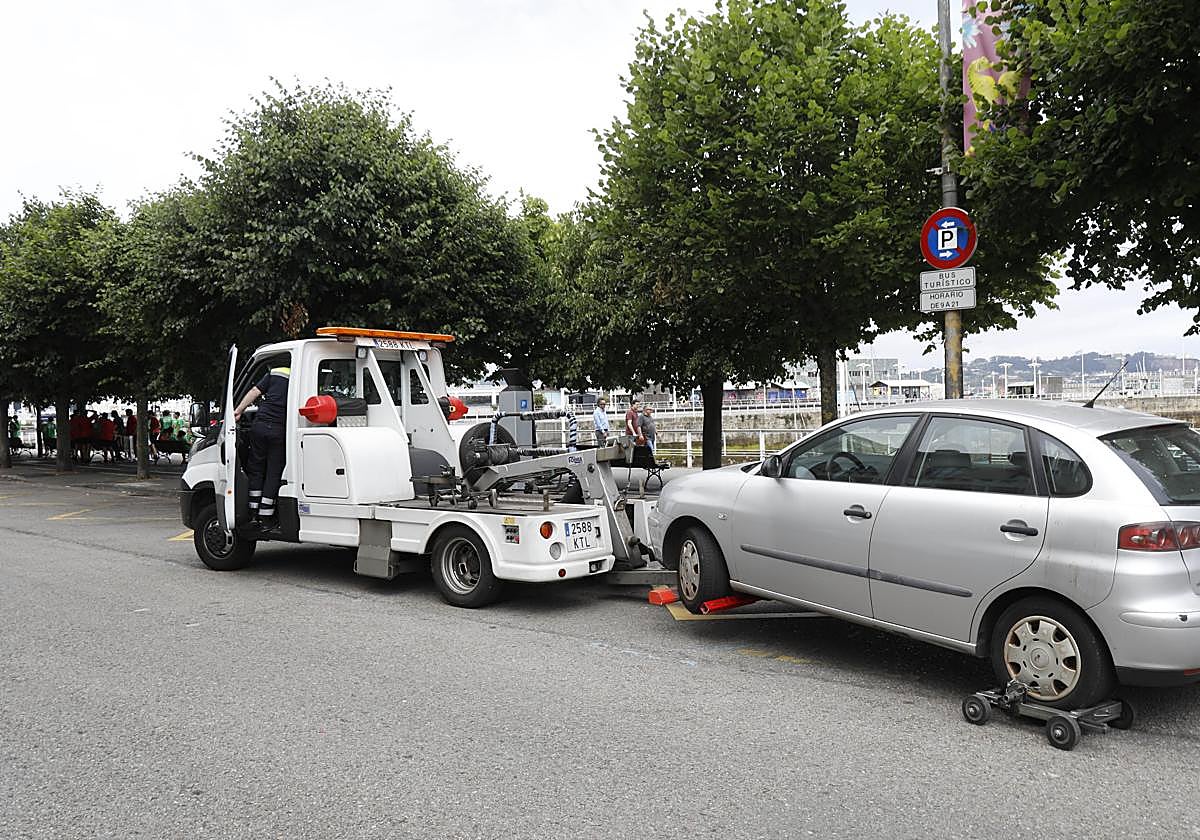Una grúa municipal retira un vehículo en una ciudad española.
