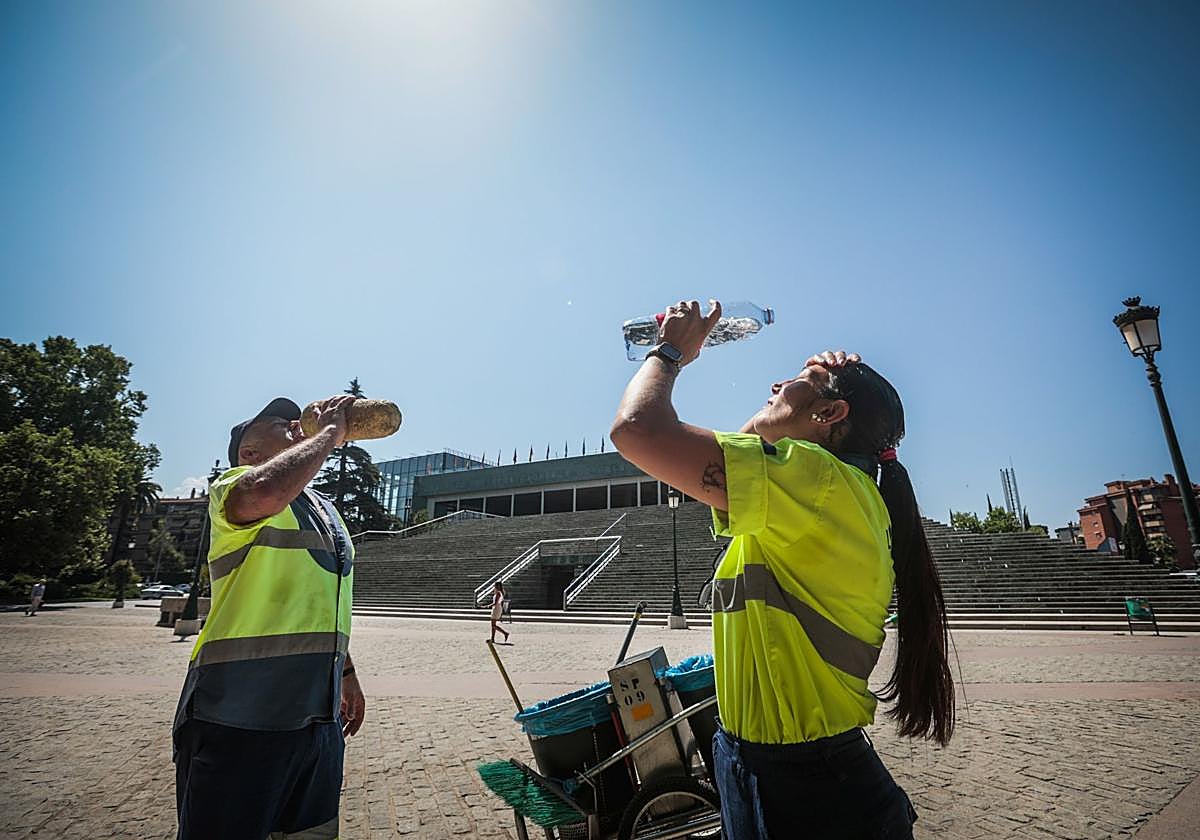 Dos trabajadores del servicio de limpieza se refrescan por el calor en una imagen de archivo.