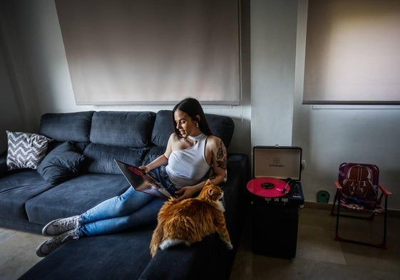 Nekane, en el salón de su casa, con su gato Santa, el tocadiscos y la silla de su hijo.