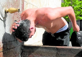 Una persona se refresca bajo una fuente ante las altas temperaturas.