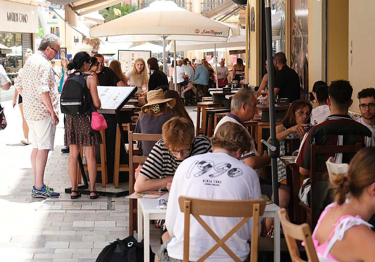 Turistas repasan la lista de precios de la carta de un restaurante.
