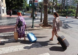 Dos turistas, maletas en mano, caminan por el centro de Almería.