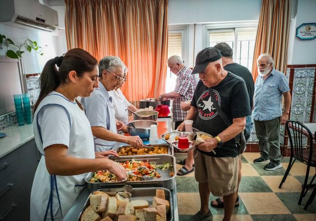 Dos religiosas y una asistenta social reparten el menú del día.