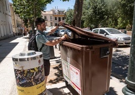 Un joven deposita una bolsa de basura orgánica en un contenedor marrón ubicado en el Campo del Príncipe