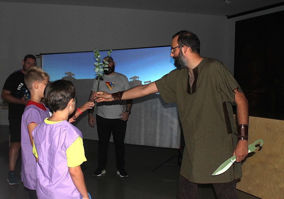 Un soldado íbero entregando una rama de olivo en señal de paz a dos participantes