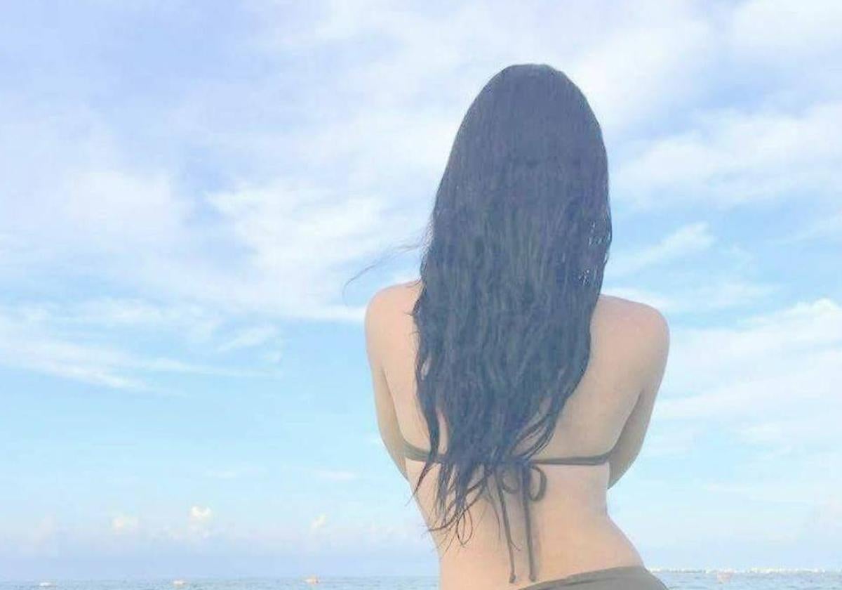 Casandra, colombiana que se gana la vida ejerciendo la prostitución, posa de espaldas en la playa.