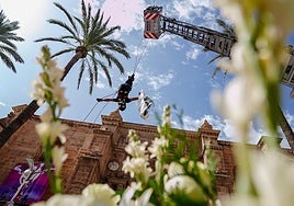 Bomberos rinden homenaje descolgándose desde un coche escalera con un ramo de flores.
