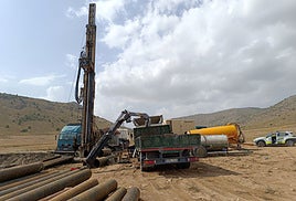 Maquinaria, tuberías y camiones en el lugar del sondeo.