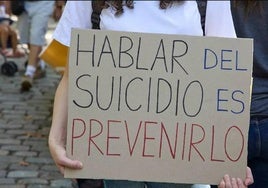 Una persona sostiene un cartel sobre el suicidio.