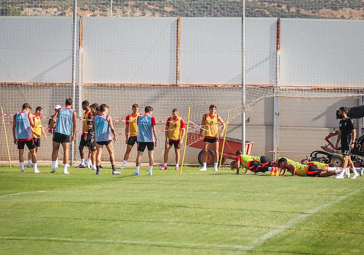 Varios futbolistas hacen flexiones durante un juego.