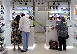 Imagen de dos farmacéuticos atendiendo a varios clientes