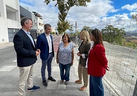 Julio Millán y varios ediles hablan con la presidenta vecinal junto al aparcamiento vallado.