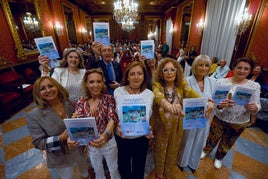 Las autores del libro posan con los representantes políticos invitados al acto y con los asistentes que llenaron el salón de plenos detrás.