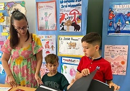 Una monitora ayuda a dos escolares en una sesión de actividades plásticas en un colegio.