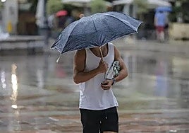 Un hombre se protege de la lluvia en una imagen de archivo