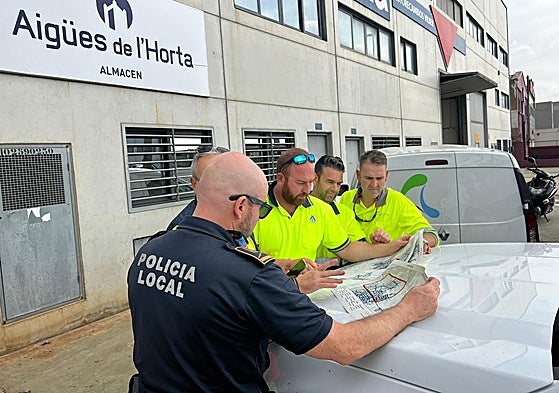 Policías y técnico estudian el plano de suministro de agua.