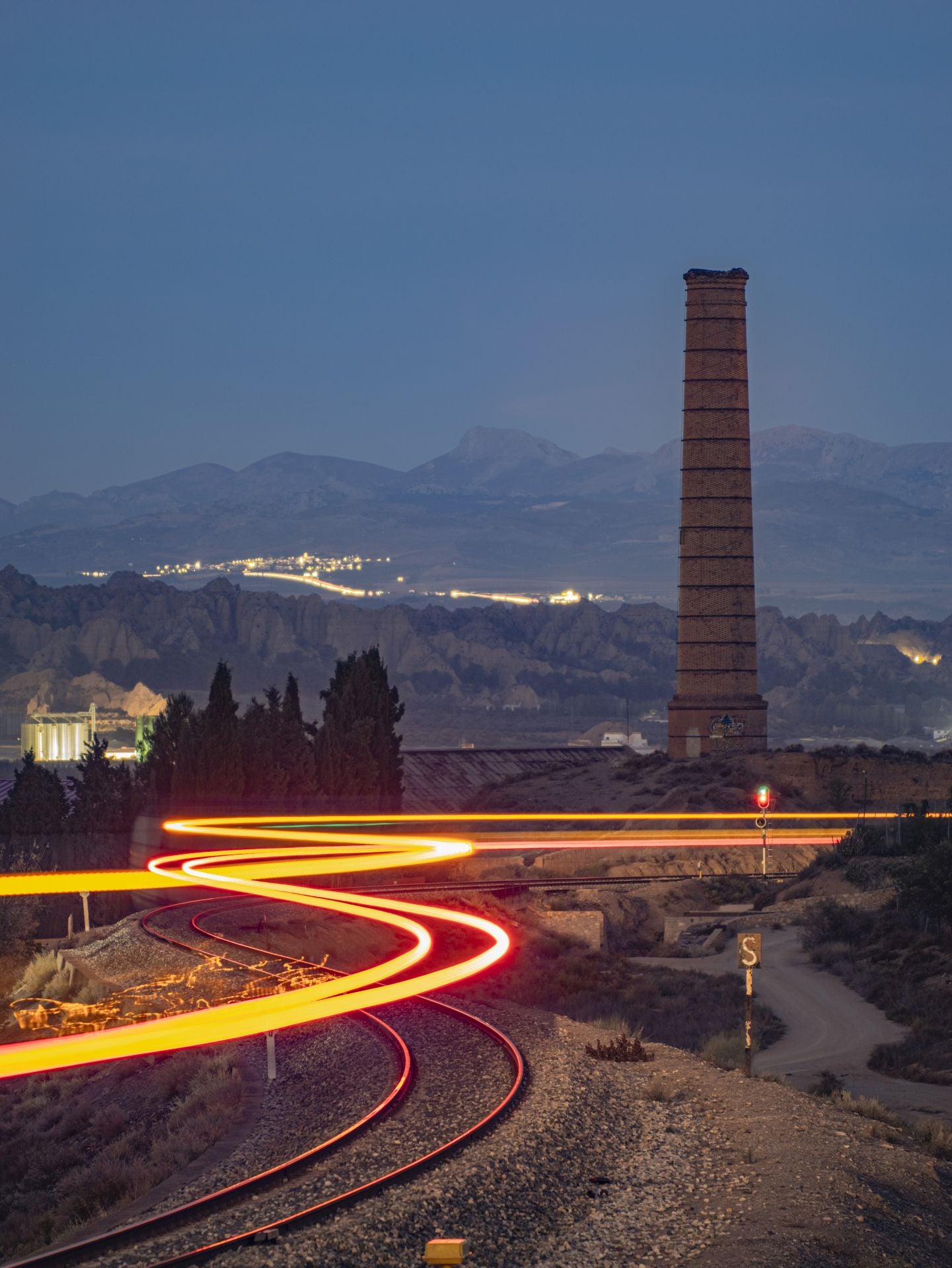 Chimenea de la Azucarera de San Torcuato de Guadix con varios pueblos del Cenete iluminados en tercer plano.