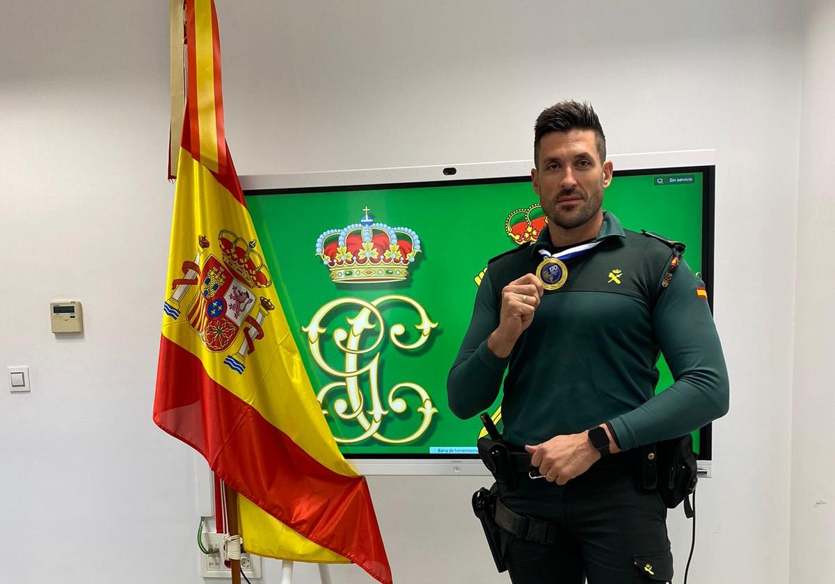 José posa con su medalla junto a la bandera nacional y su uniforme de la Benemérita.