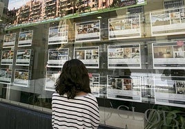 Una joven observa carteles de viviendas a la venta en un tablón en una imagen de archivo.