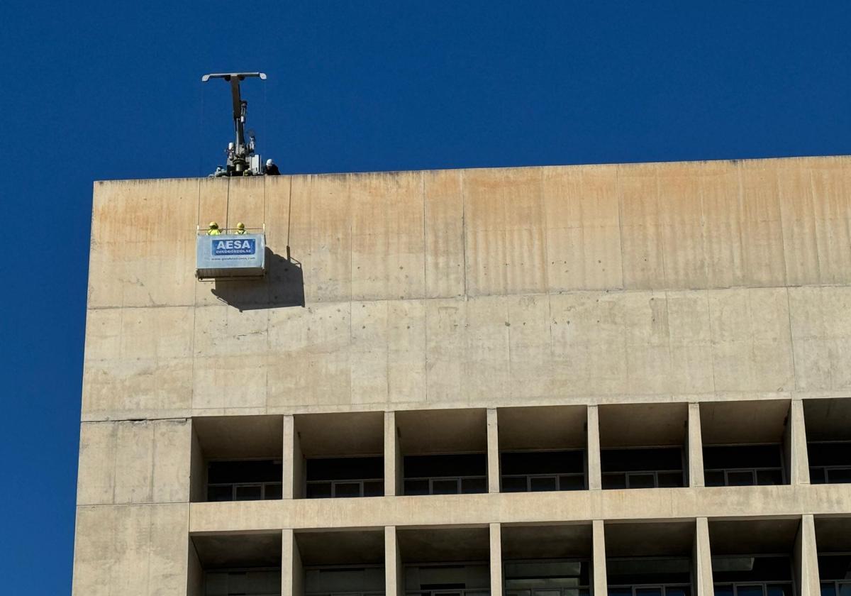 Operarios trabajan en a retirada del logo de La Caixa del Cubo.