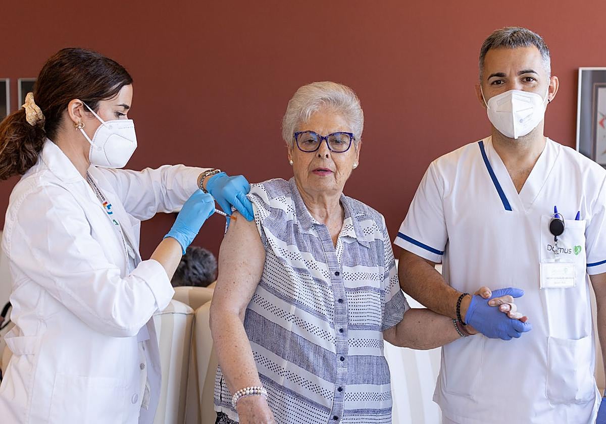 Una enfermera administra la vacuna de la gripe a una mujer en una residencia de mayores.