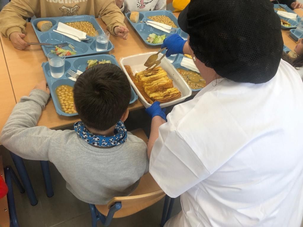 Una monitora sirve tortilla francesa en el comedor del CEIP 'Virgen del Río', de Huércal-Overa