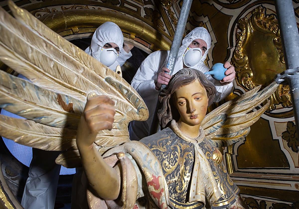 Auxiliares, provistos de equipos de protección personal, limpian una de las esculturas situadas a trece metros de altura.