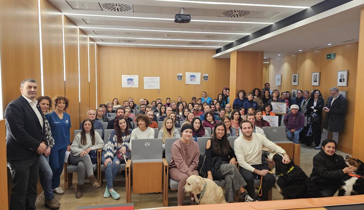 Imagen principal - Aspecto del salón de actos, con perros entre los asistentes. En la mesa, Marian Díaz, Raúl Pedregosa, Francisco Cerezuela y Ana Martínez.