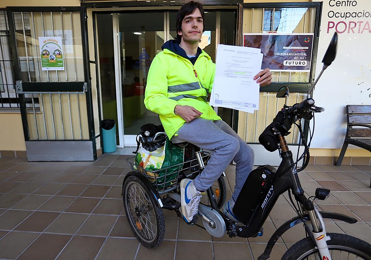 Adrián posa con su certificado de discapacidad caducado ante la sede de Aspace.