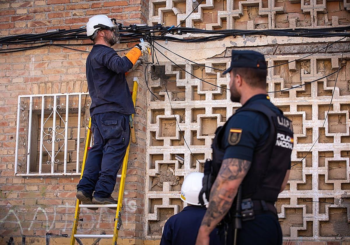 Dos técnicos de Endesa retiran enganches ilegales a la red en una redada.