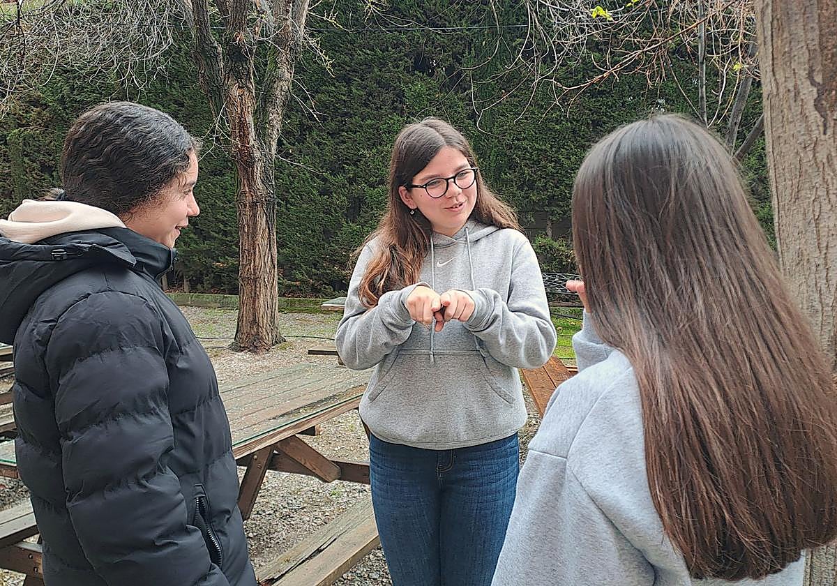 Alba Morales se comunica con dos compañeras en lengua de signos.