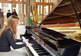 Una joven toca el piano en la entrada del Palacio Provincial de la Diputación.
