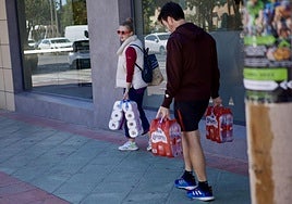 Varios ciduadanos cargan con agua y papel higiénico.