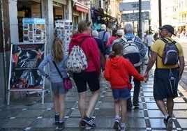 Una familia de turistas con mochilas a sus espaldas pasea por la calle Reyes Católicos.