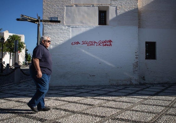Un vecino pasea por delante de la fachada de la iglesia de San Nicolás, donde un vándalo ha realizado una pintada con spray de color rojo.