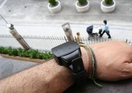 Un hombre, muestra una pulsera de control del sistema Viogén.