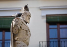Carlos V, sin su brazo derecho y dos palomas sobre su cabeza, en la plaza de la Universidad.