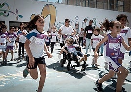 La atleta granadina María Pérez empuja el carro de Elenita rodeada de compañeros de la niña en el colegio Maristas, de Granada capital.