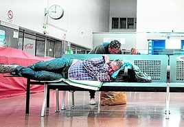 Una persona duerme recostada en la única silla que al no tener reposabrazos permite tumbarse a lo largo en el interior de la estación de autobuses de Granada.