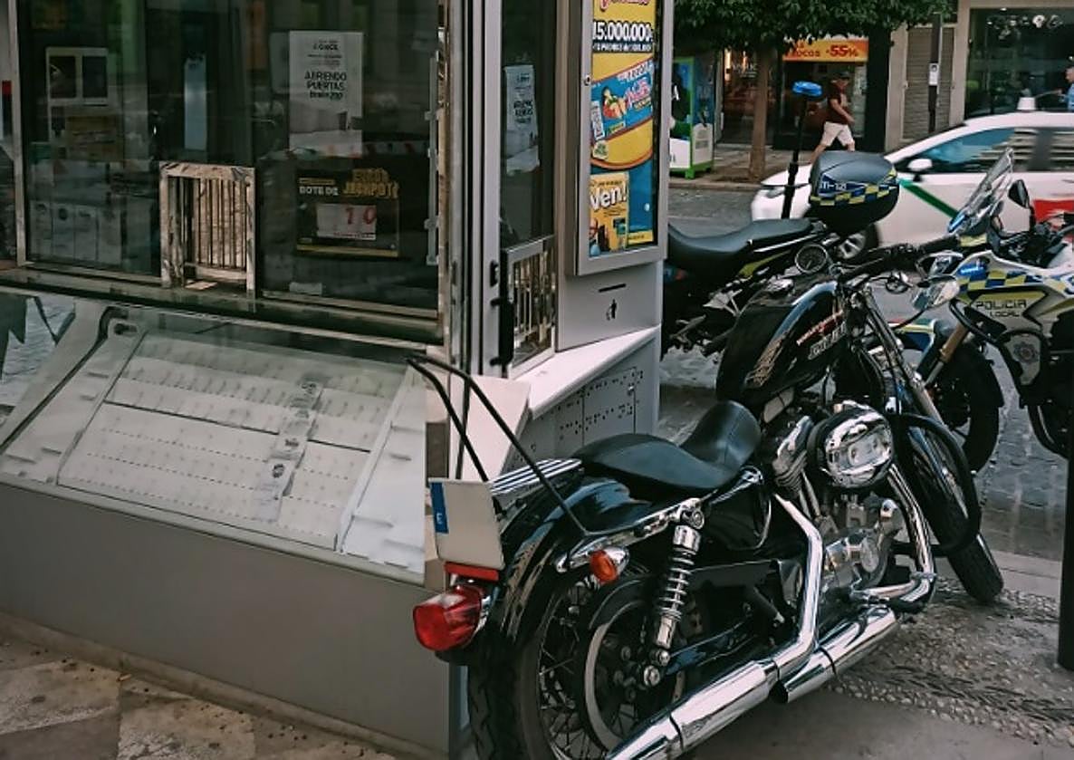 Aparca la moto en la puerta de un quiosquero de la ONCE y sobre la acera.