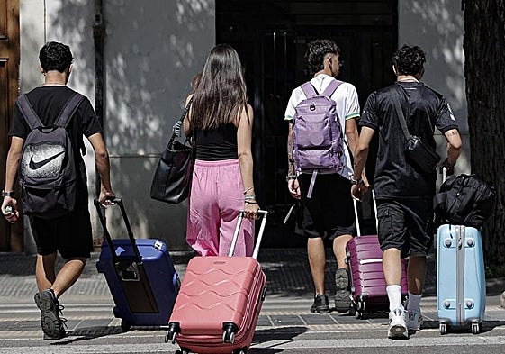 Un grupo de jóvenes turistas, maleta en mano.