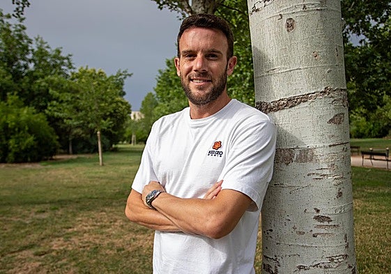 Quini, sonriente apoyado en un árbol.