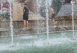 Jóvenes buscan refrescarse en la fuente de la plaza de la Constitución, en Jaén.
