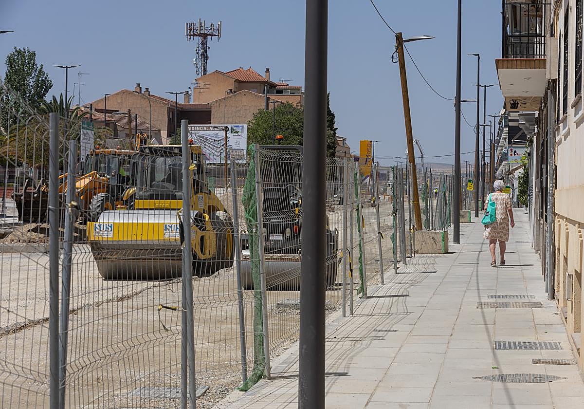 Una mujer camina por la acera mientras las máquinas trabajan en la plataforma del metro.